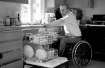 Man in wheelchair emptying dishwasher
